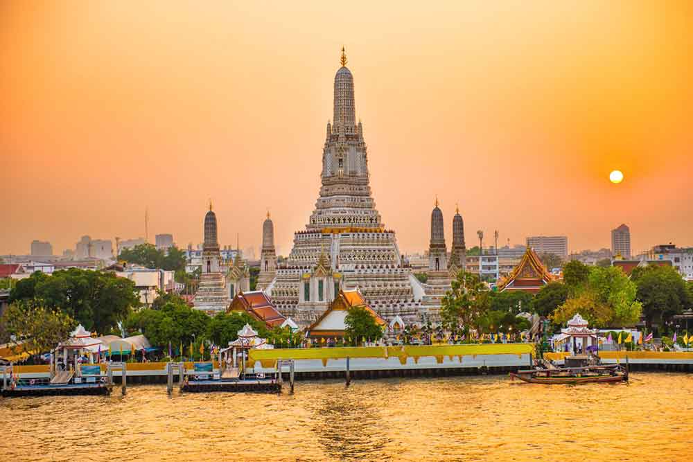 How to Spend a Month in Thailand: Best 1 Month in Thailand Itinerary 6 Wat Arun and boats on Chao Phraya River at sunset with shining sun