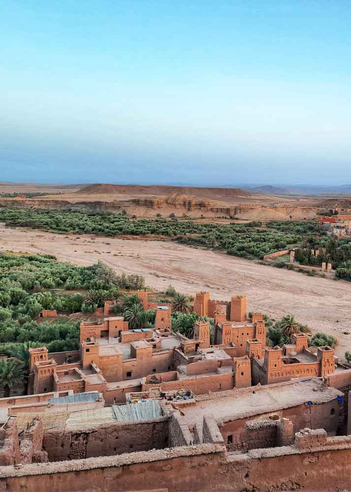 From the top of Ait Ben Haddou, a mesmerizing view unfolds, revealing the majestic earthen walls, trees, and the landscape 