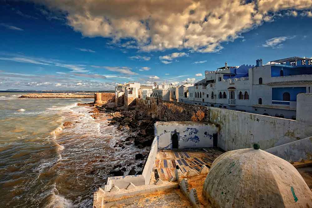 Combination of white-washed and blue buildings along with the beach in Asilah
