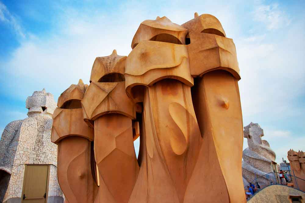 Barcelona Bucket List: 32 Best Things to Do in Barcelona, Spain 7 Casa Mila rooftop showcases the twisted brown chimneys under a clear blue sky