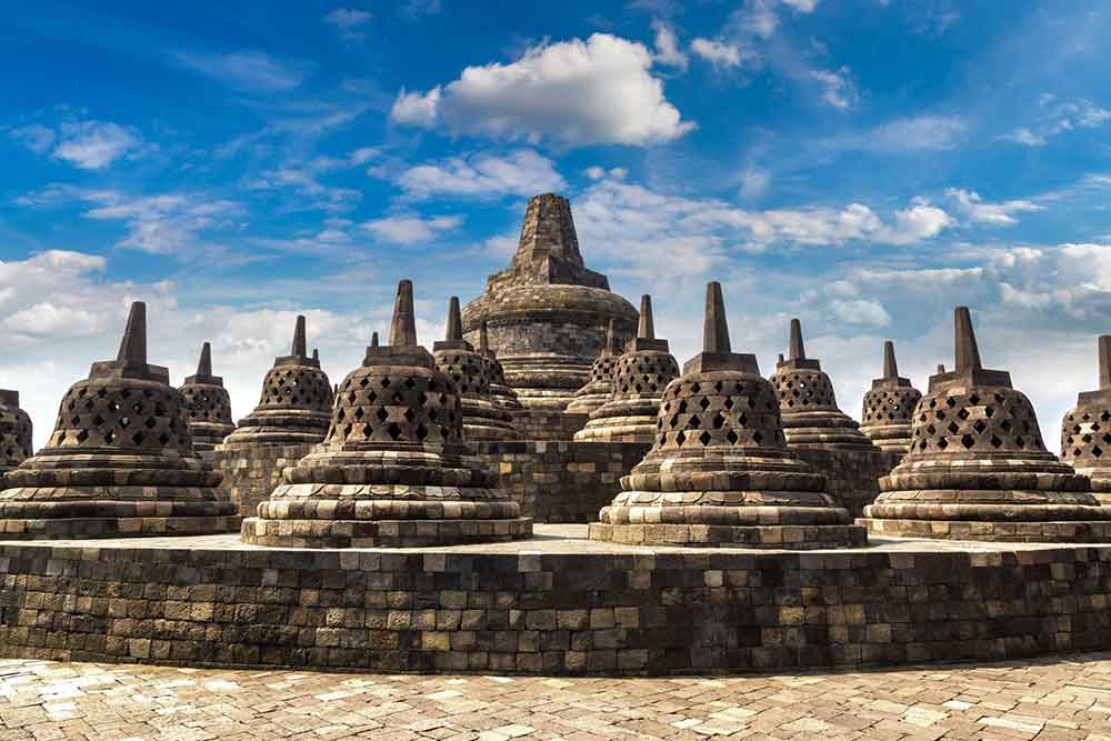 Borobudur, Java - a monumental temple with multiple bell-shaped stupas stands tall in a clear blue sky