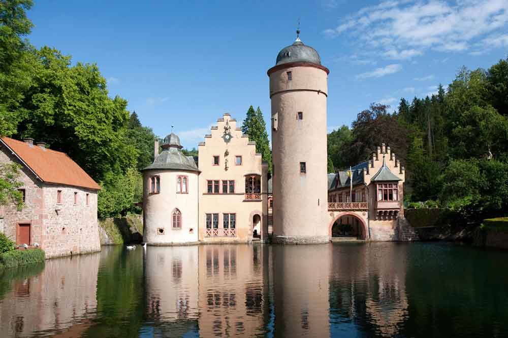Mespelbrunn Castle in Germany showcase the big column with a dome at the top surrounded by lake and trees 