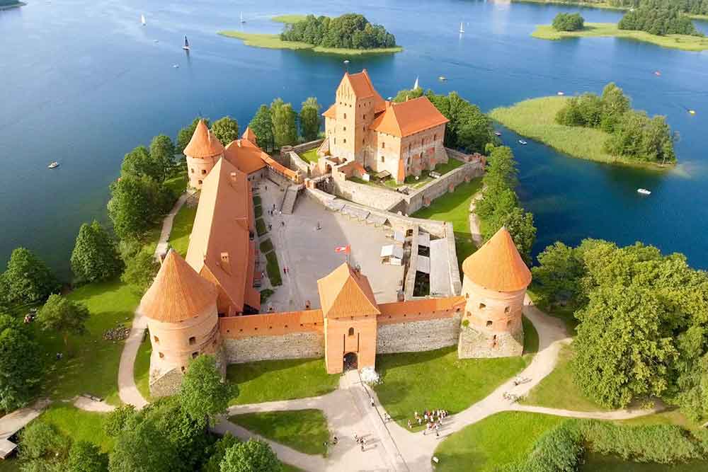 Aerial view of Trakai Castle in Lithuania with its red brick walls and towers surrounded by tranquil waters of Lake Galve