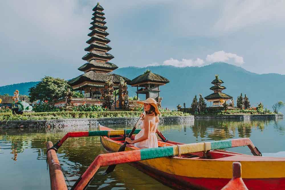 Girl rowing a boat with a background of Ulun Danu Beratan Temple in Bali