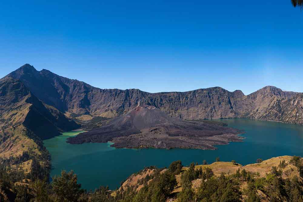 Mount Rinjani, Lombok features a stunning blue lake inside the crater with trees  