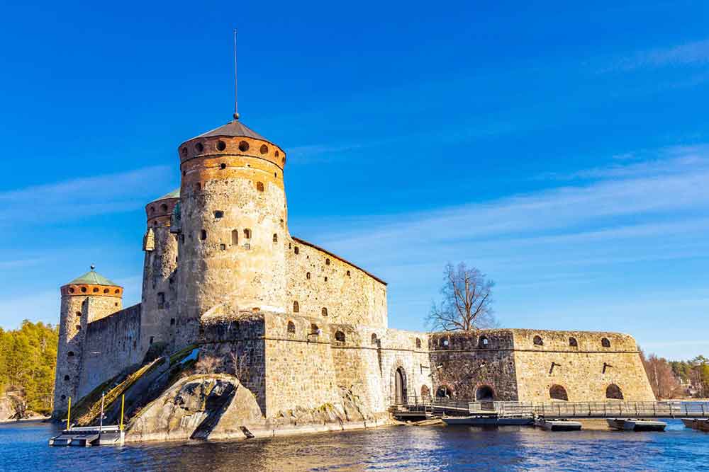 Olavinlinna Castle, Finland with its sturdy stone walls, high battlements and prominent towers reflecting in the calm waters of the lake