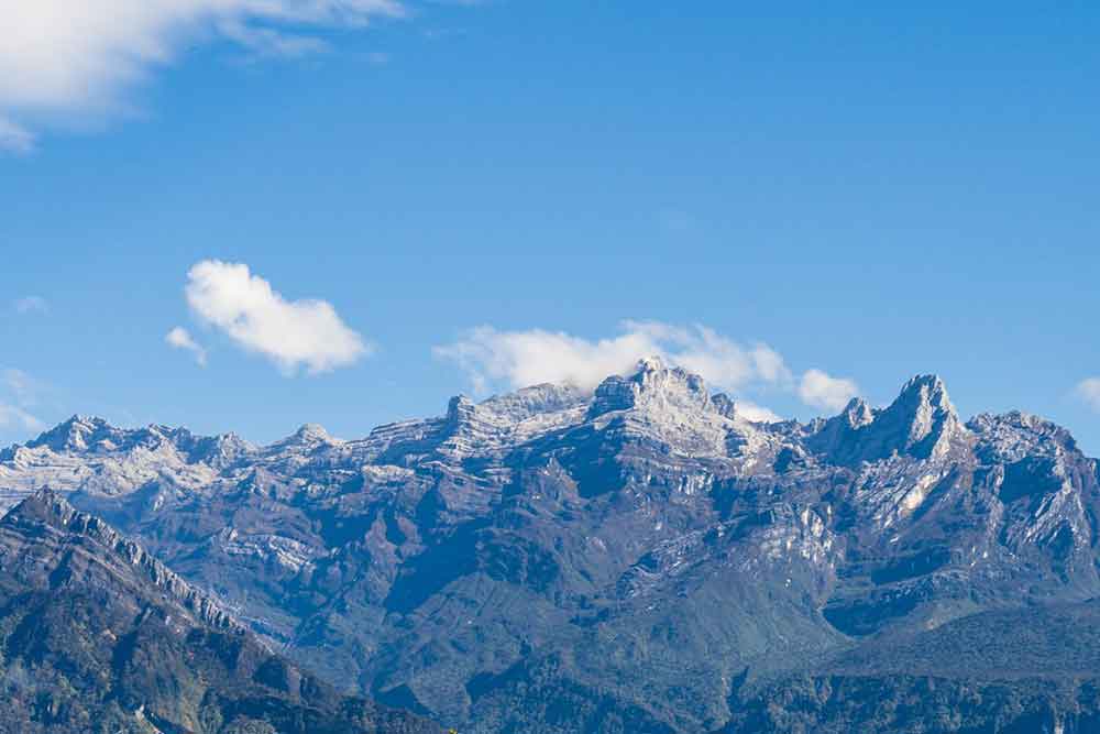 Puncak Jaya, Papua - a glaciated mountain, and its upper slopes are covered in snow with a blue sky in a background
