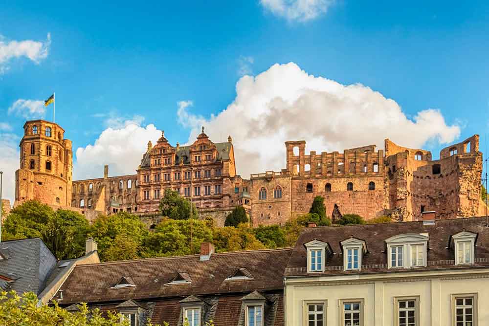 Heidelberg Castle, Germany features a red sandstone walls punctuated by tower and multiple windows perched on the slopes of the hill 