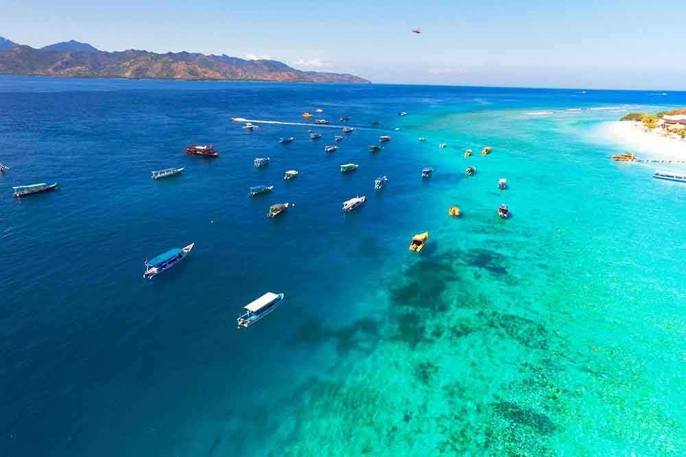 Gili Islands, Lombok with its turquoise water with sailing boats and mountains at the background