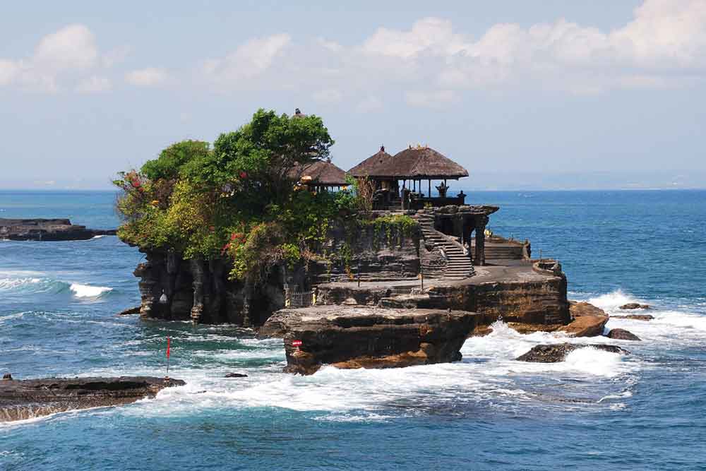 Tanah Lot located on a rock formation off the coast in Bali, Indonesia featuring the Temple with pagodas that stands tall against the backdrop of the open sea