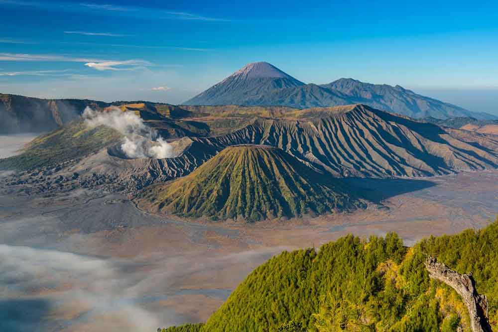 Mount Bromo in East Java offers breathtaking views of the surrounding volcanoes emitting a flow of white smoke