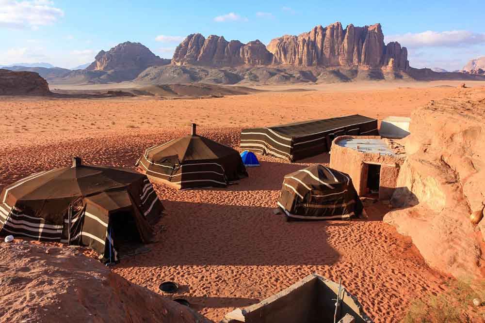 7 Best Wadi Rum Jeep Tours, Jordan: Choosing the Best 4x4 Wadi Rum Experience 11 Black tent camp in Wadi Rum Desert, with red-orange sands and rock formations in the background