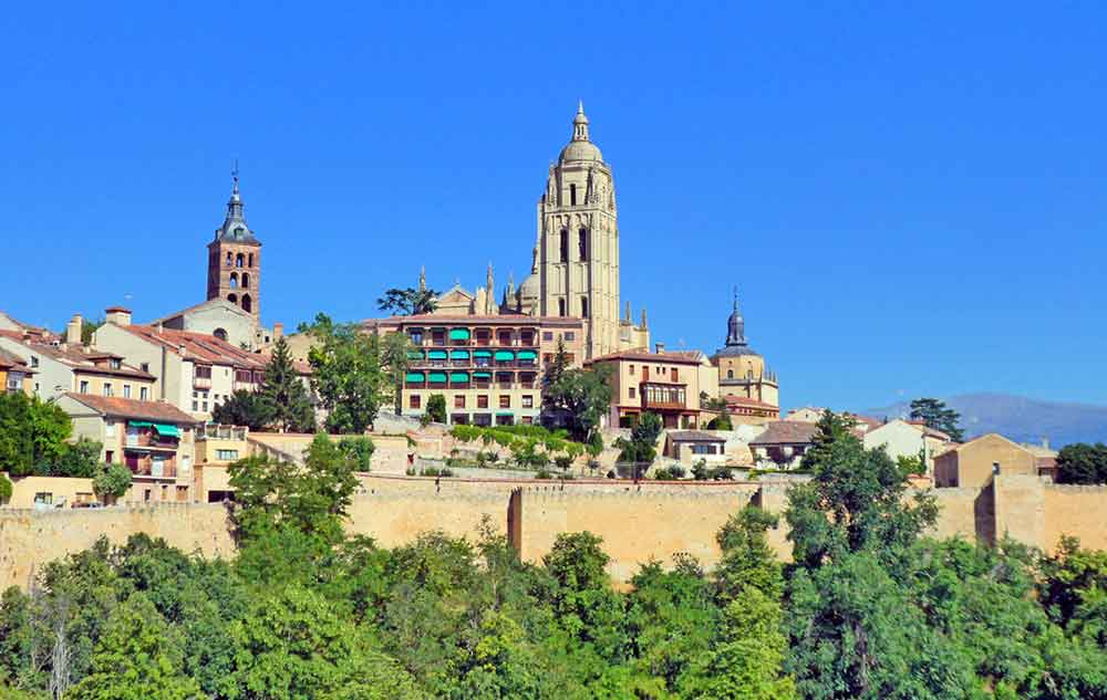 Is Segovia Worth Visiting? How to Visit Segovia From Madrid in a Day 13 View of the City walls in Segovia with trees, buildings and houses