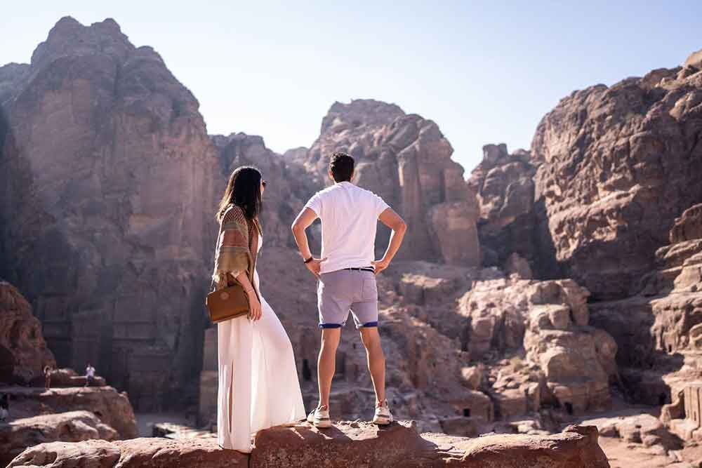 A couple stood looking out over Petra ruins from above.
