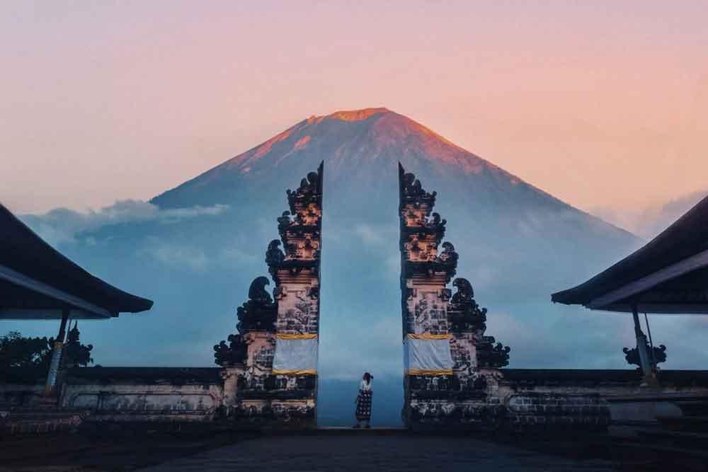 Girl standing between the Gates of Heaven at Lempuyang Temple with mountains on the background