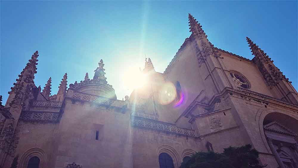 Is Segovia Worth Visiting? How to Visit Segovia From Madrid in a Day 9 Segovia Cathedral with its brown walls and intricate spires illuminated by a sunlight on a sunny day with a blue sky in a background