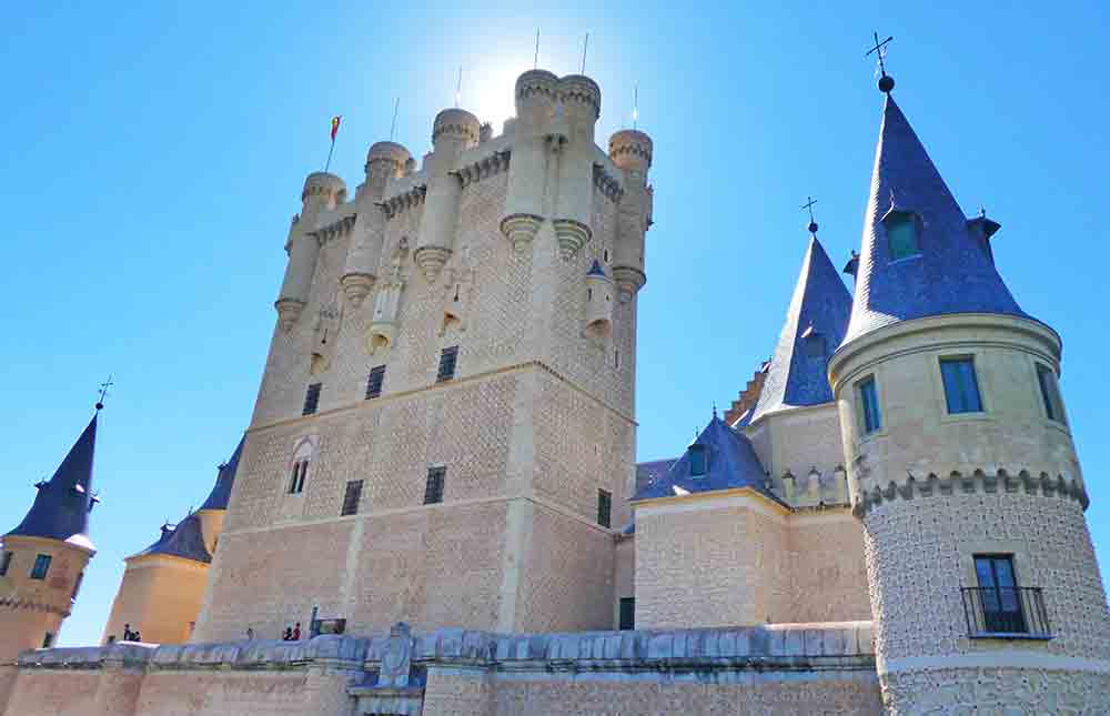 Is Segovia Worth Visiting? How to Visit Segovia From Madrid in a Day 6 The Segovia Alcazar - a castle adorned with Rapunzel-style towers, and buildings topped by a perfectly cone-shaped blue roof.