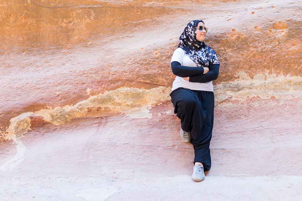 Woman wearing a Hijab, sunglasses, white shirt, long black pants and practical shoes at Petra Jordan  