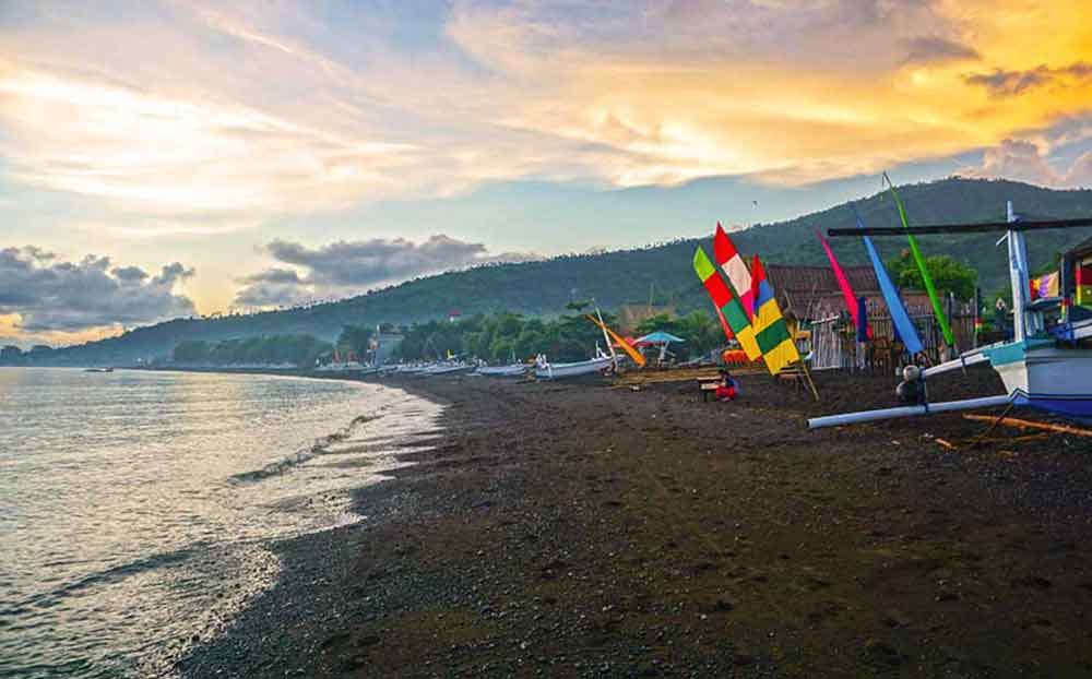 Sunrise on Amed Beach with brown sand and boats