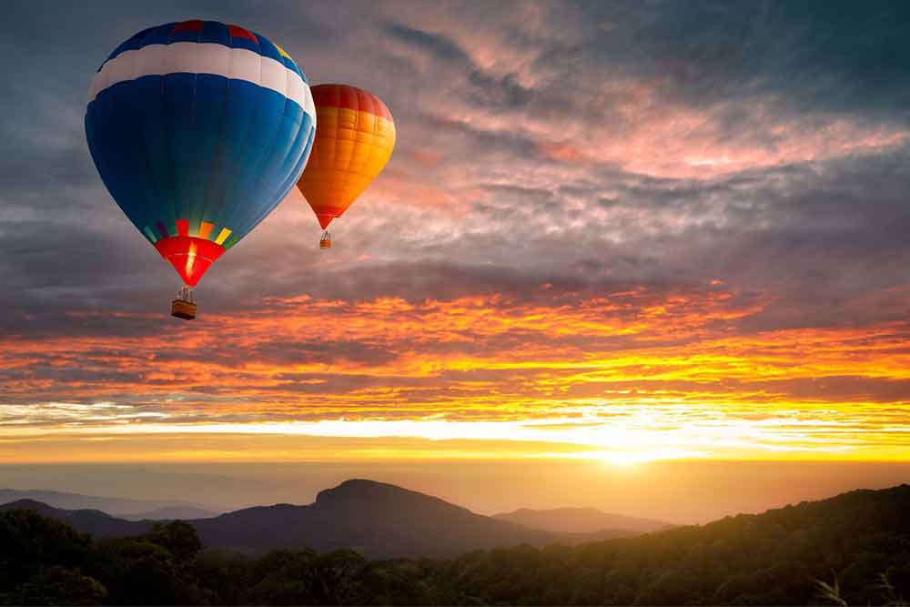 Two hot air ballons flying high during sunset