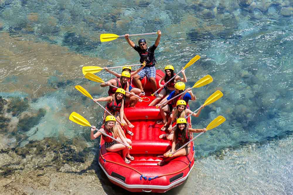 Taking a group picture raising their yellow rowing equipments before the white water rafting activity at Slovenia