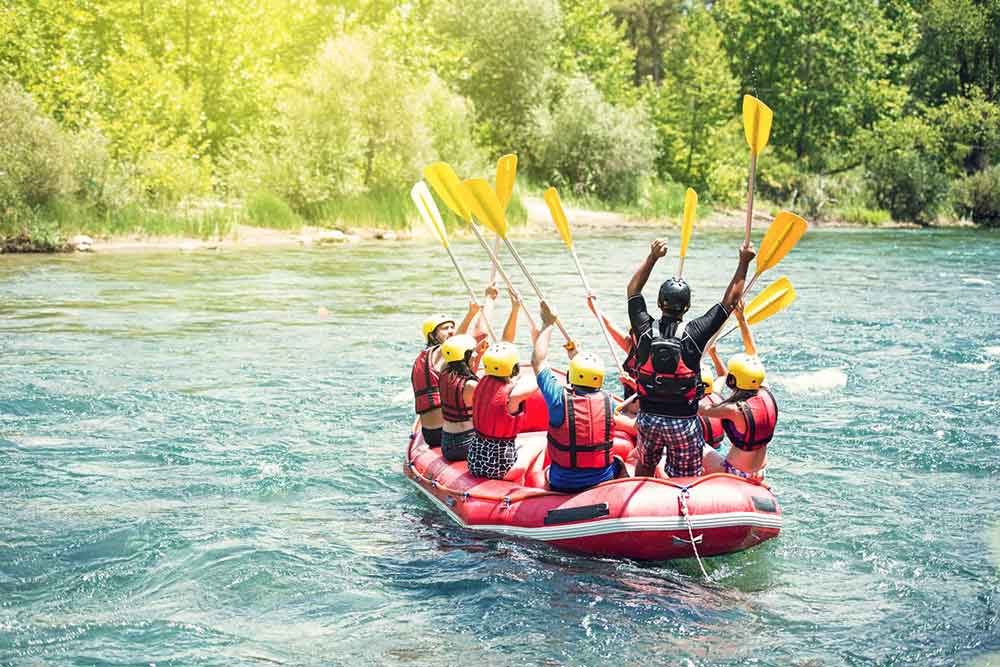 Group of friends raising their yellow rowing equipment while at the middle of the water in Slovenia