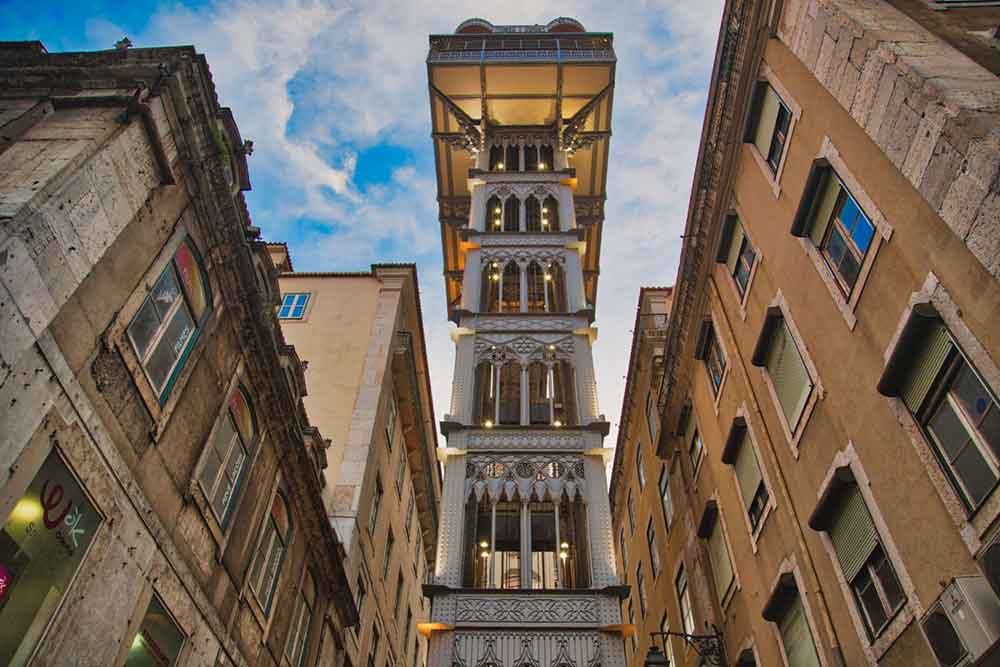 The Santa Justa Elevator - an elegant iron structure features decorative arches and windows that stand talls in the heart of Lisbon surrounded by buildings.
