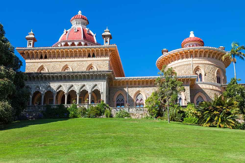 Palácio de Monserrate in Sintra is a unique palace with two connected buildings; one has a squared roof, while the other features a round roof, a green lawn extends in front of the palace