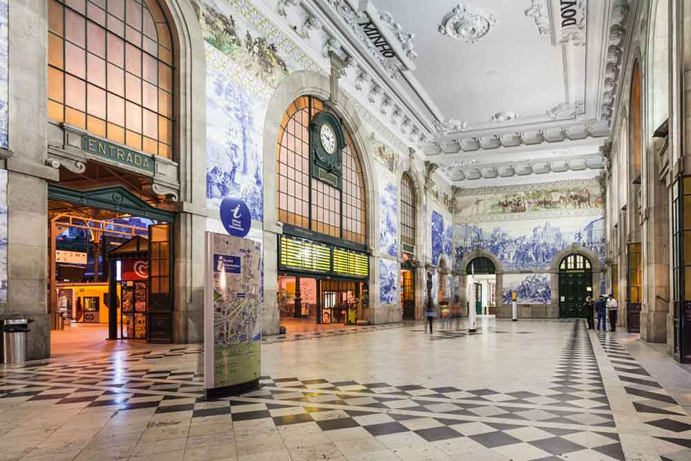 San Bento Train Station greets visitors with a spacious lobby area characterized by high ceilings and ornate decorations, featuring a central clock.