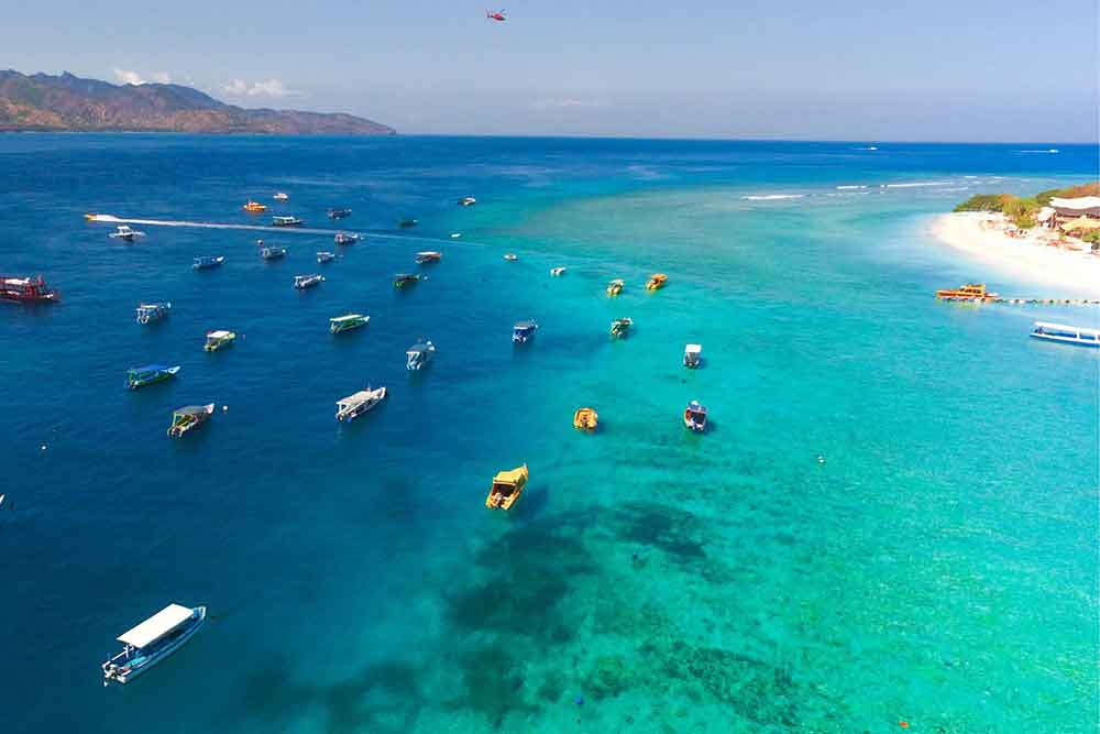 33 Best Hidden Coves and Secluded Beaches Around the World 3 An aerial view of the Gilli Islands in Indonesia presenting a stunning scene with numerous boats gently dotting the blue turquoise waters below