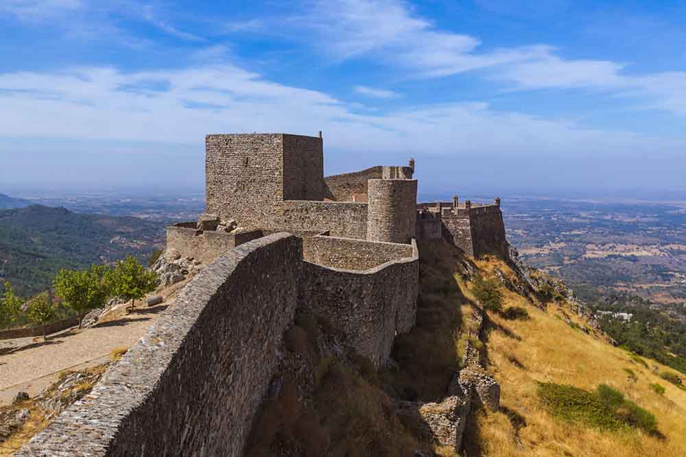 Marvão Castle is a medieval fortress featuring stark and thick granite walls, offering a stunning view of the surrounding landscape and city.