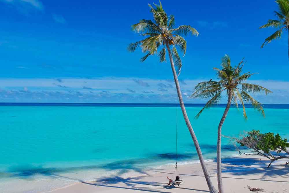 33 Best Hidden Coves and Secluded Beaches Around the World 1 A stunning Secluded Beach showcasing its blue water and white sand beach with a tourist and palm trees