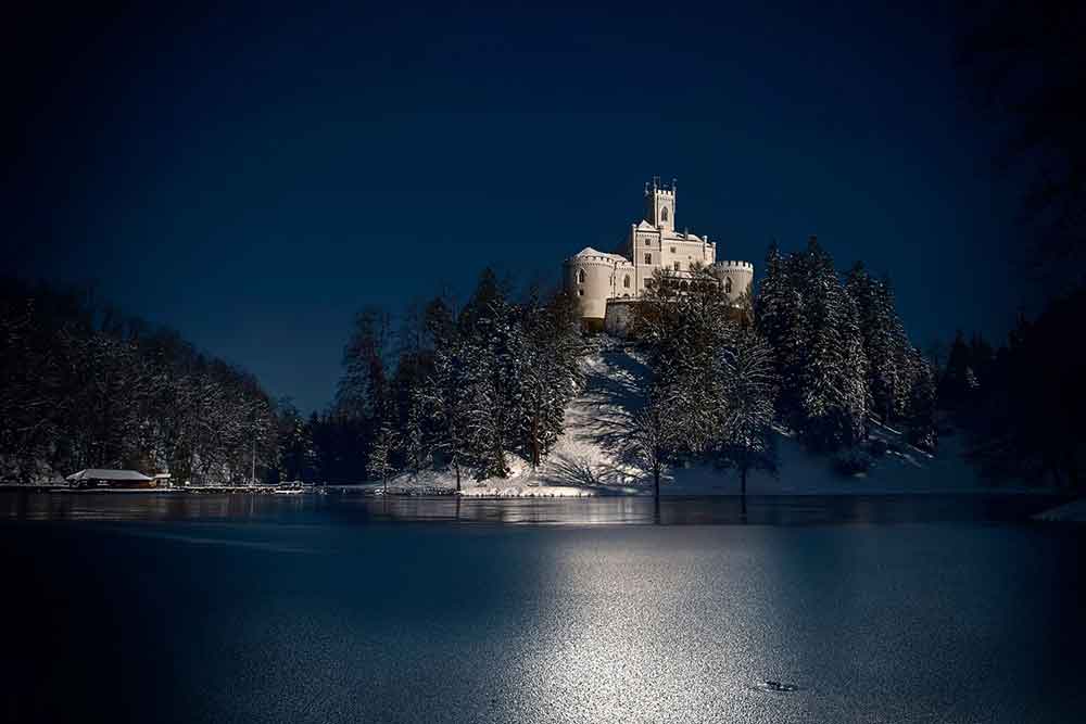 Trakošćan Castle in Croatia on a hill in the snow illuminated by the moonlight 