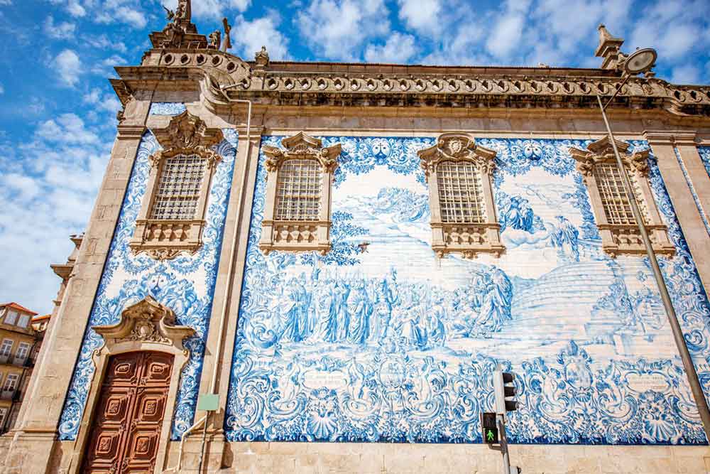 Blue artwork featuring people and ornate details painting on one of the walls of a building in Porto.