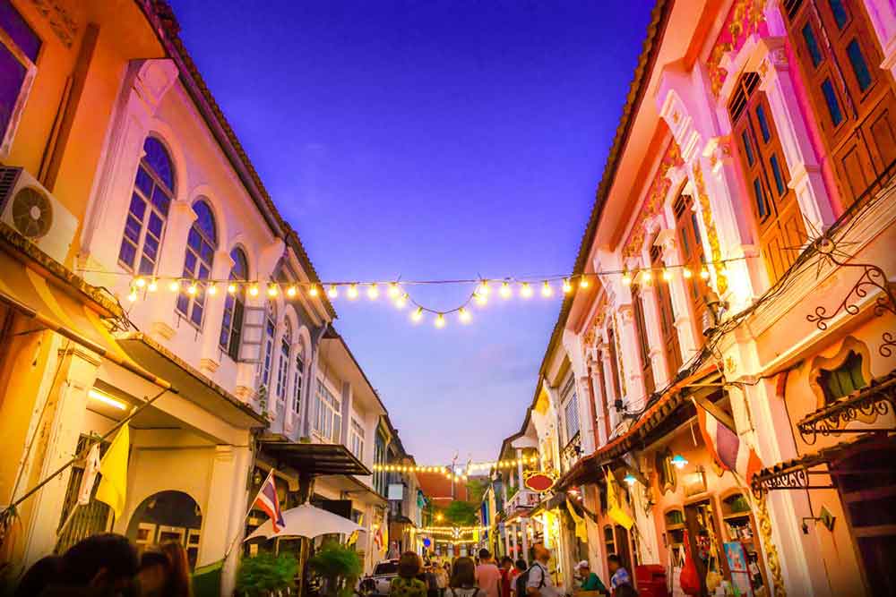 Street night market in Phuket, Thailand with crowds of people exploring the various stalls and illuminated by the vibrant lights 