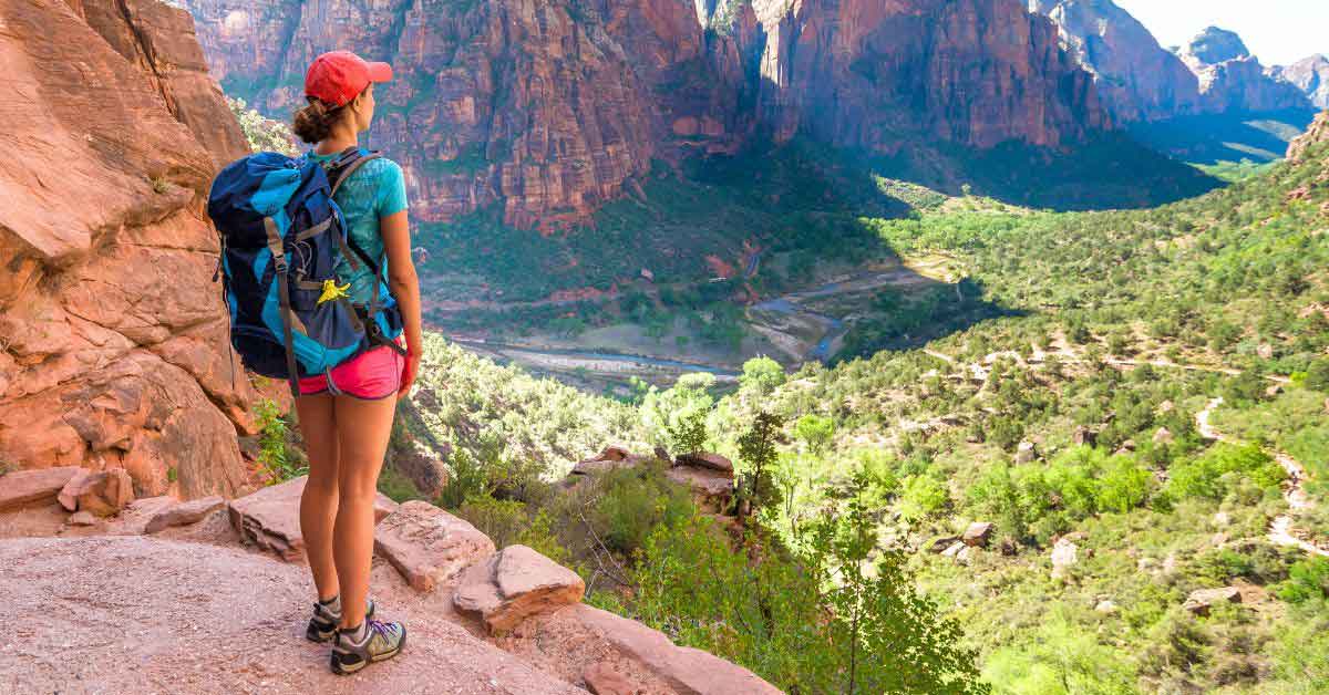 Travel Planning 2 A woman wearing a backpack looking out over a valley with mountains and trees.
