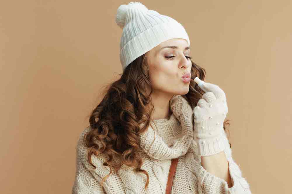 Best Packing for Winter in Europe Guide: Hand Luggage Only Packing List for Winter in Europe 12 Woman applying chapstick and wearing a winter clothes