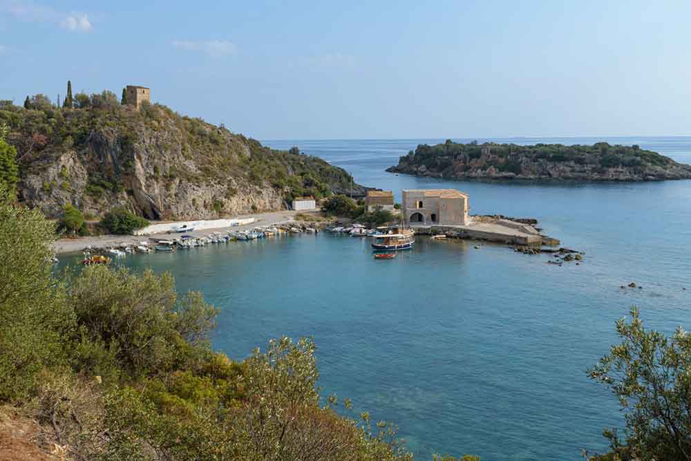 Is Peloponnese Worth Visiting? 15 Reasons to Visit the Peloponnese Region, Greece 9 small Kardamyli village in Messenia, Peloponnese showing a small harbour with small block shaped buildings and small fisheman boats.