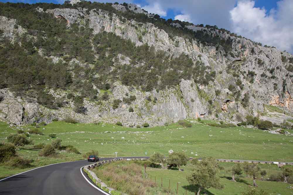 A road going through farmland in Grazalema Natural Park with a giant karst in the background. 