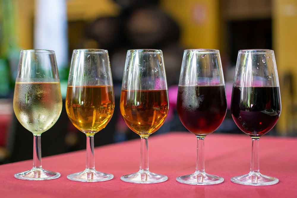 A line of 5 glasses of sherry starting with a light staw coloured one on the left,  going to a dark brown one on the right. Try the sherry in Jerez de la Frontera