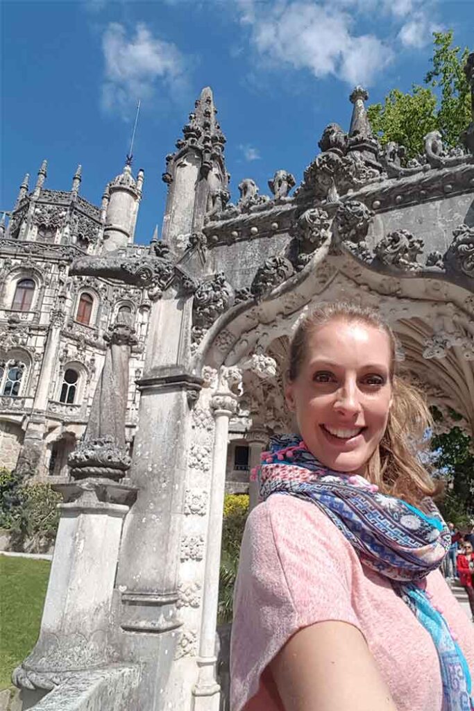 The entry arch and palace are in the Gothic style with lots of ornate features. They are a light grey stone. There is a photo of me stood infront of the entry arch at Quinta da Regaleira.