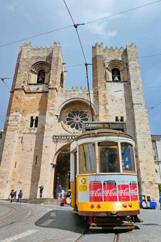A yellow tram going past the Lisbon Cathedral