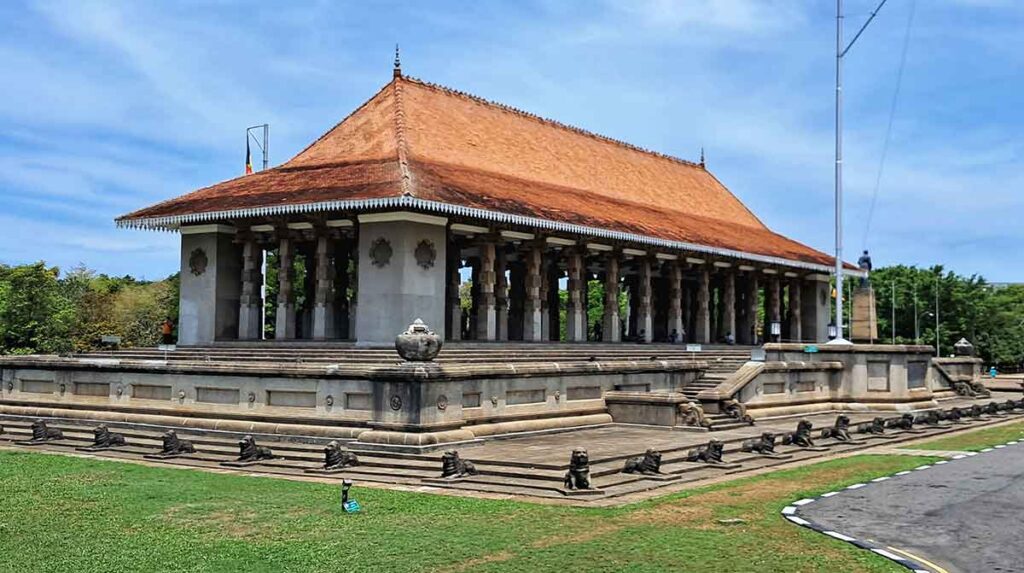 The temple-like structure of Independence Squarewith columns supporting a red roof, surrounede by seated lions outide. 