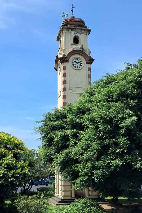 The Khan Clock Tower in with it's square shaped footprint, looks a little like a minaret. There are lookout windows at the top, a red roof and a clock on each face. 