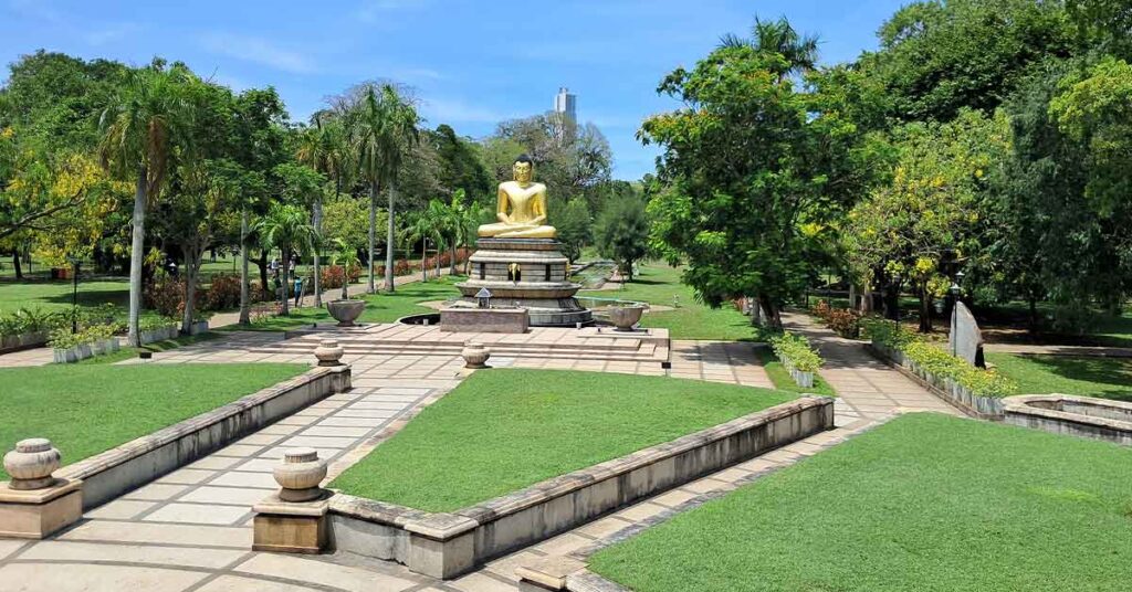 A seated golden Buddha on a plinth in Viharamahadevi Park.