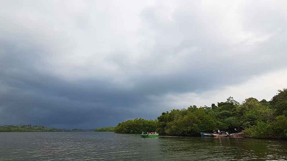 A dark grey cloud over the mangroves with two small boats
