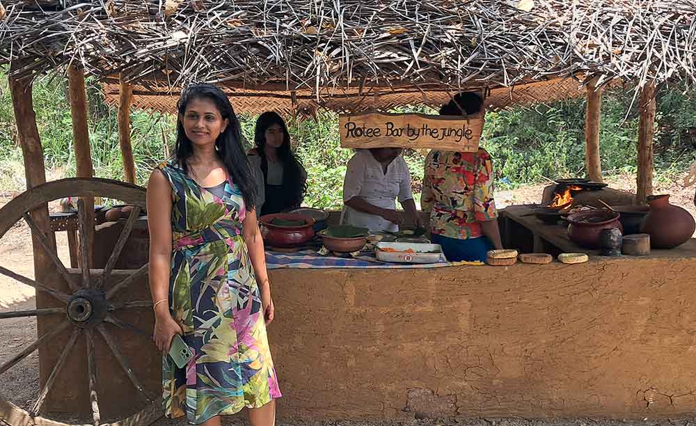A Sakun, the owner of Eco Pavillion,  in a colourful dress standing in front of the outdoor kitchen with her family. 