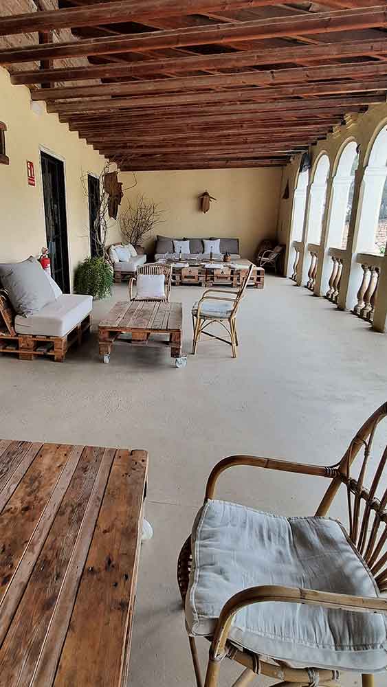 Best Montserrat Tour from Barcelona (With Tapas + Winery Visit) 19 A large covered balcony with arched windows on one side. There are seats and tables with a rustic look.