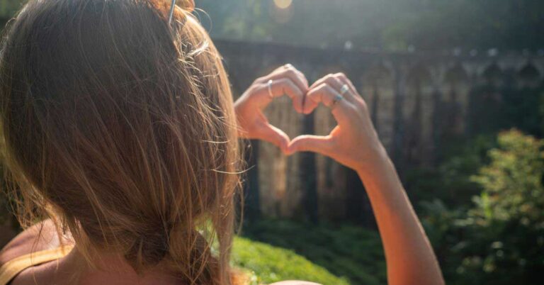 Image of a lady making a heart shape with her fingers at nine arches bridge in Sri Lanka. If you're wondering is Sri Lanka worth visiting, then read these 10 great reasons to visit Sri Lanka - you won't be dissapointed.