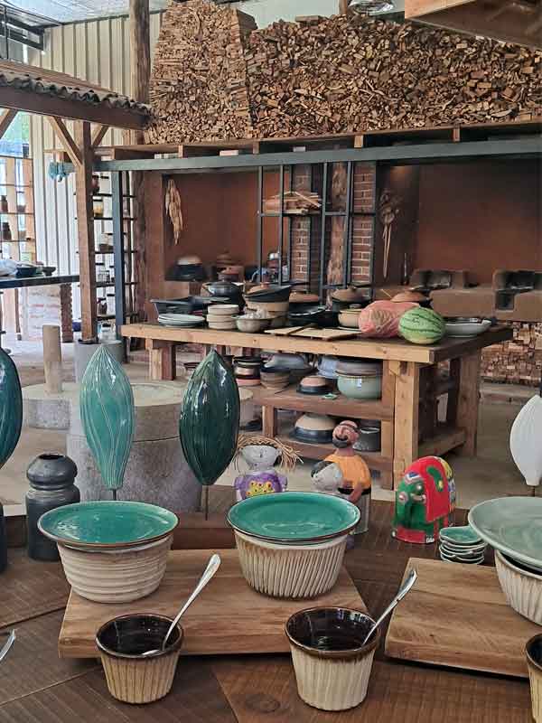 An open plan kitchen made of reclaimed wood and fitted out with traditional ceramic pots made on site. 